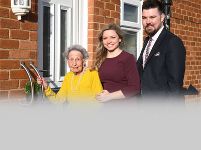 Housing associations staff outside front door of improved home solutions